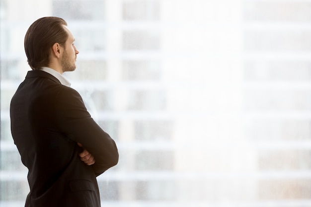 Free Photo businessman dreamily looks in window at office