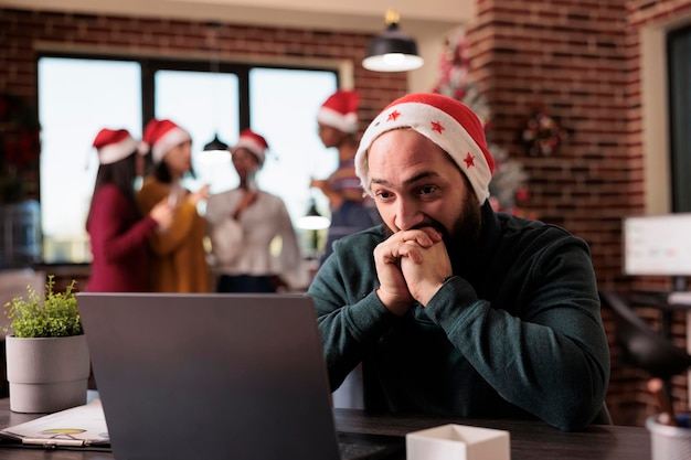 Free photo businessman feeling disturbed at office job because of noisy coworkers celebrating christmas eve. tired irritated employee being overwhelmed and working during winter holiday season.