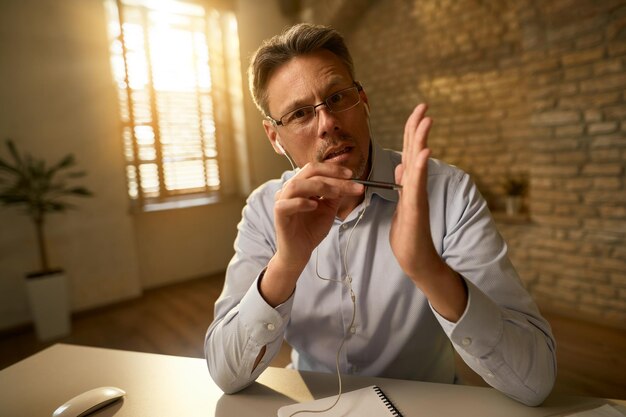 Businessman gesturing explaining something while while working in the office and looking at the camera