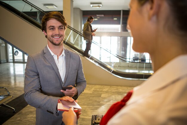 Businessman giving his boarding pass to the female staff at the check in desk