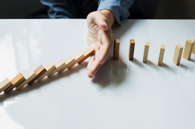 Free photo businessman hand stop dominoes continuous toppled or risk with copyspace