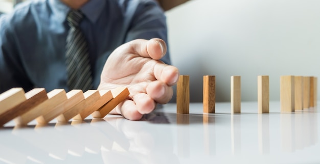 businessman hand stop dominoes continuous toppled or risk with copyspace