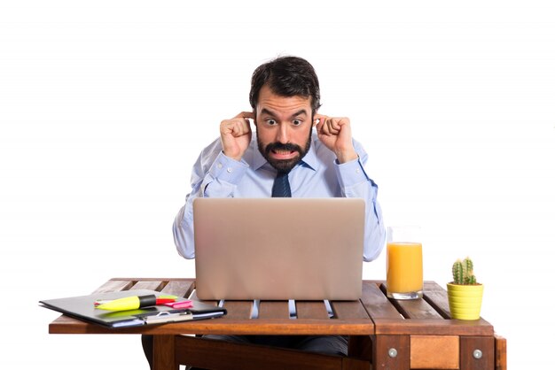 Businessman in his office covering his ears