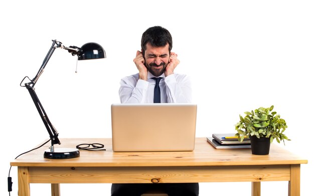 Businessman in his office covering his ears