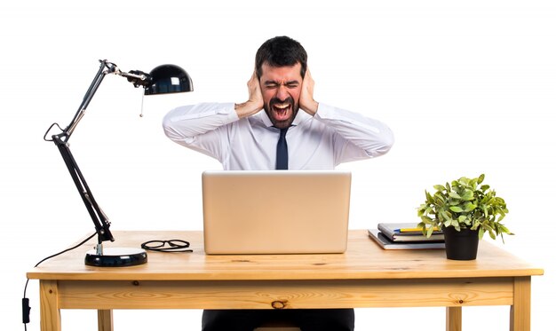 Businessman in his office covering his ears