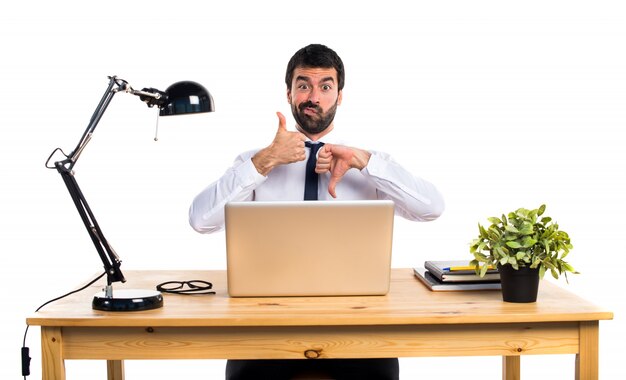 Businessman in his office making good-bad sign