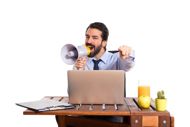 Free photo businessman in his office shouting by megaphone