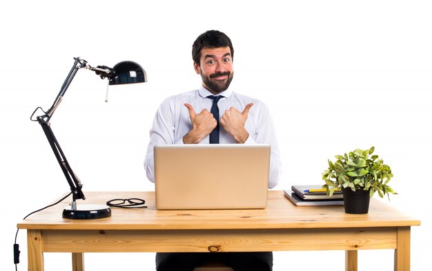 Businessman in his office with thumb up