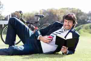 Free photo businessman holding an apple and a book outdoors