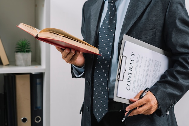 Free photo businessman holding book and clipboard with contract