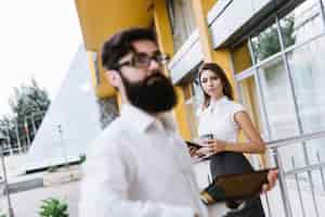 Free photo businessman holding digital tablet standing in front of businesswoman at outdoors