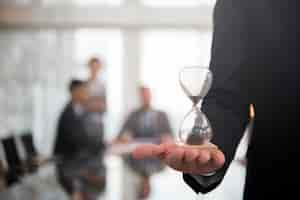 Free photo businessman holding an hour glass, signifies the importance of being on time