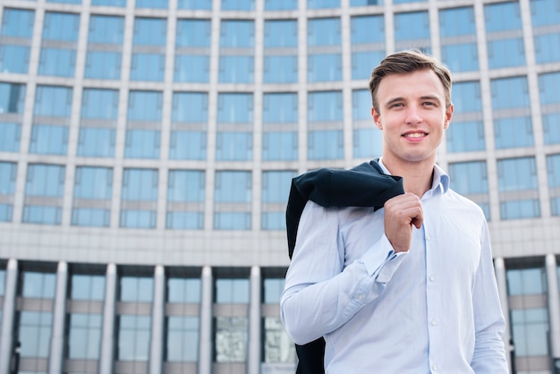 Free photo businessman holding jacket looking at camera