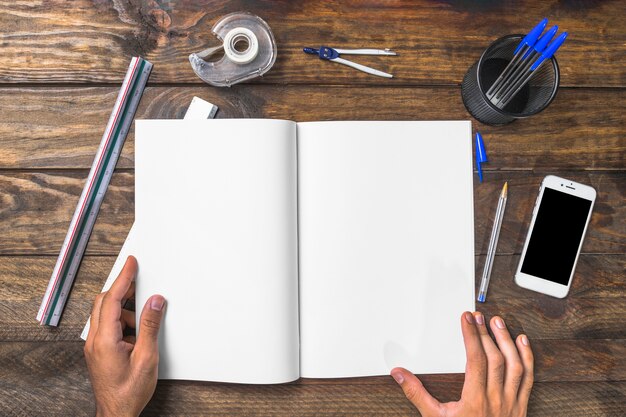 Businessman holding white paper surrounded with stationeries and cellphone