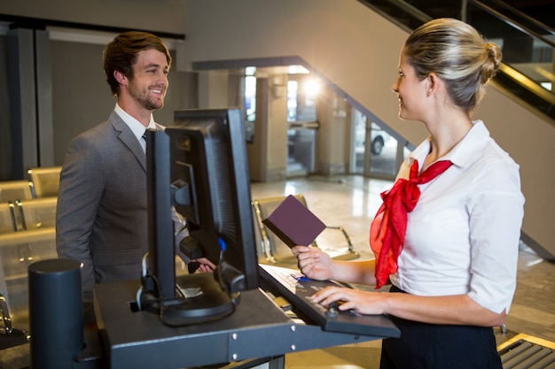 Free photo businessman interacting with female airport staff at the check in desk