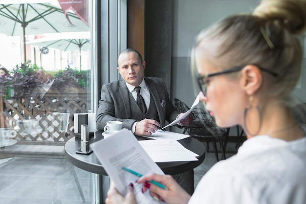 Free photo businessman looking at his colleague examining document in caf�