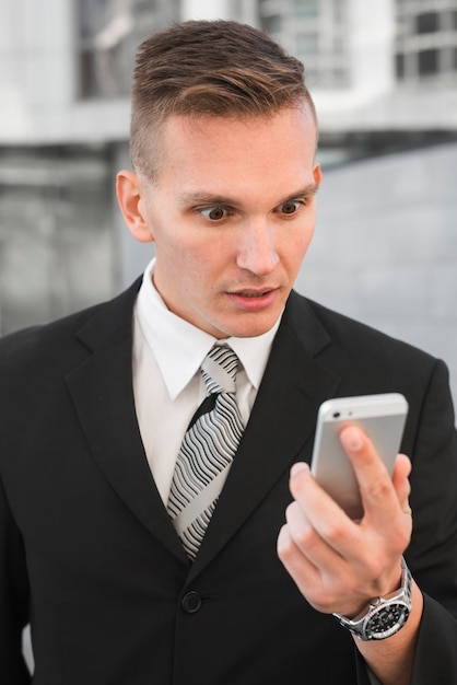 Businessman looking at smartphone with surprised expression