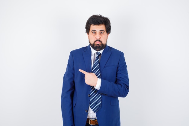 Free Photo businessman pointing left with index finger in formal suit and looking serious , front view.