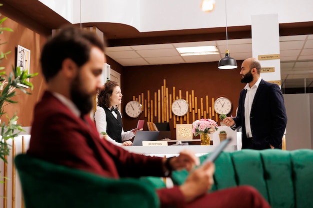 Free Photo businessman provides information at front desk for check in procedure, travelling on work purposes to attend official conference. receptionist greeting professional client in lobby.