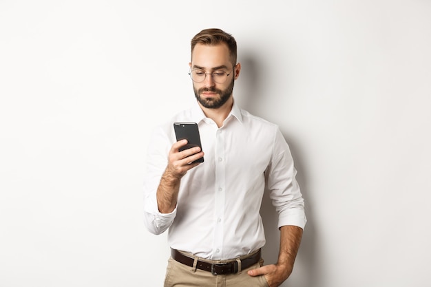 Businessman reading message on phone, standing  .