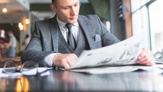 Free photo businessman reading newspaper in caf�