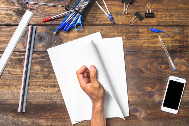 Free Photo businessman's hand holding white paper with stationeries and cellphone on table