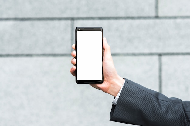 Free Photo businessman's hand showing blank mobile screen against blurred backdrop