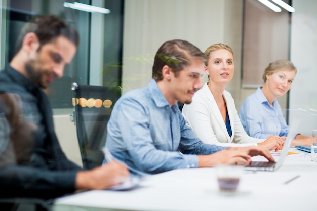 Free photo businessman sitting in front of a laptop with colleagues at the sides