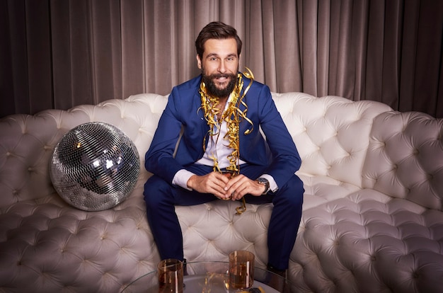 Free photo businessman sitting on sofa at night club