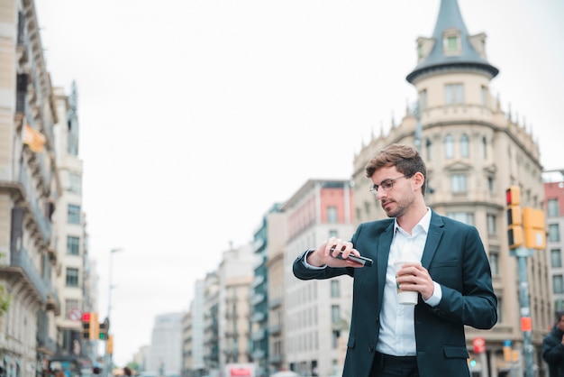 Free photo businessman standing on city street watching time on his wrist watch