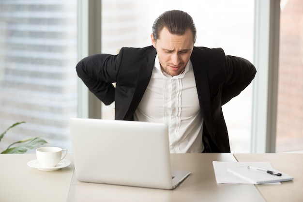 Businessman suffering from backache at workplace