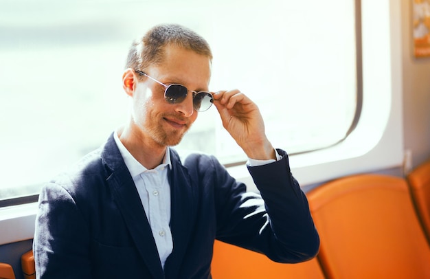 Businessman in sunglasses on subway Good looking middle aged man wearing shirt and jacket fixing his sunglasses while sitting inside of metro train