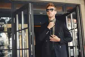 Free photo businessman talking on the phone and holding a folder in his hands. man in sunglasses.