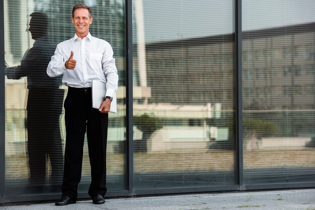 Businessman thumbs up near building