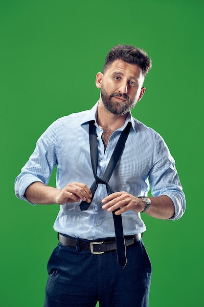 Free photo businessman tying his tie at studio