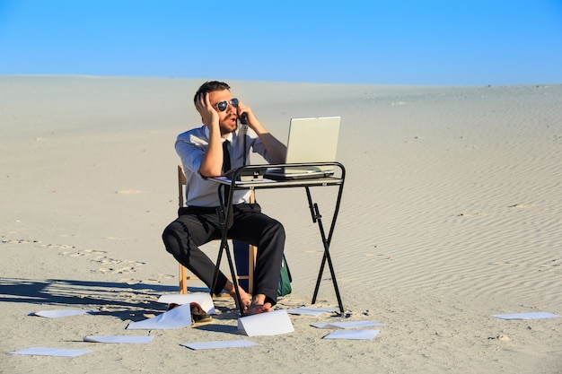 Free Photo businessman using laptop in a desert