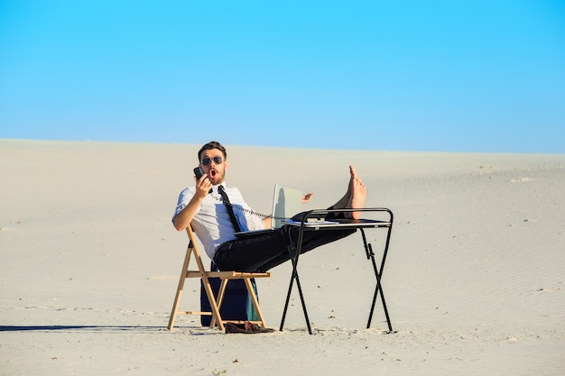 Free photo businessman using  laptop in a desert