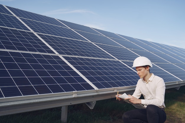 Businessman in a white helmet near solar battery