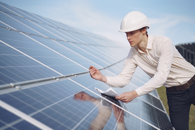 Businessman in a white helmet near solar battery