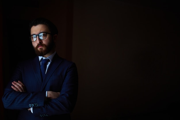 Free photo businessman with crossed arms in the darkness