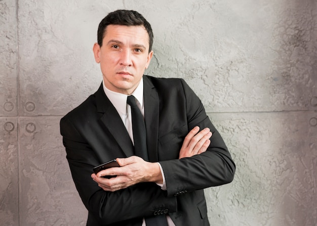 Businessman with crossed arms leaning on wall