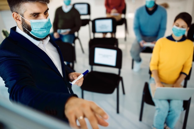 Free Photo businessman with face mask giving a presentation on whiteboard in board room