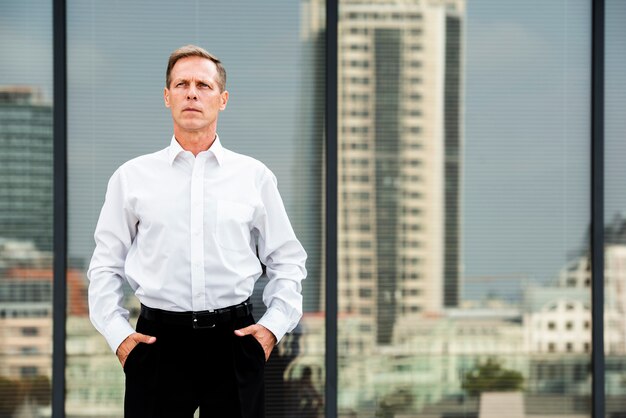 Businessman with hands in pockets near glass building