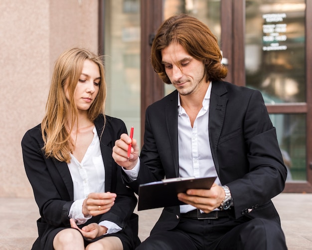 Free photo businessman with his colleague signing on a clipboard