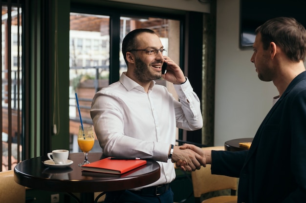 Free Photo businessman with smartphone greeting man