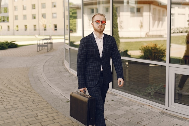 Businessman with suitcase walking in a summer city