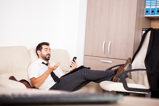 Businessman working in the office on the couch putting long hours of work. Businessperson in professional environment