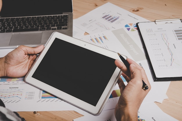 Free photo businessman working with blank screen digital tablet and laptop on wooden desk in office.