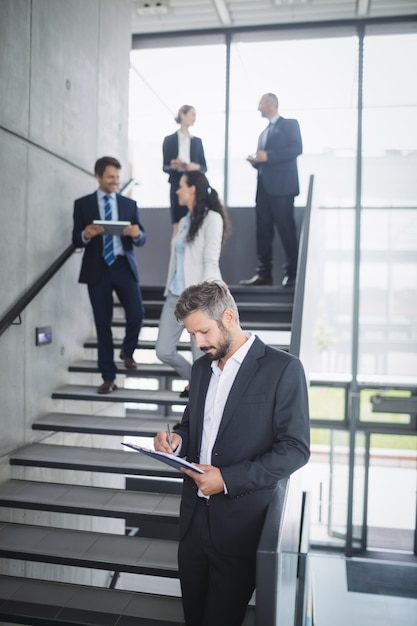 Businessman writing on clipboard