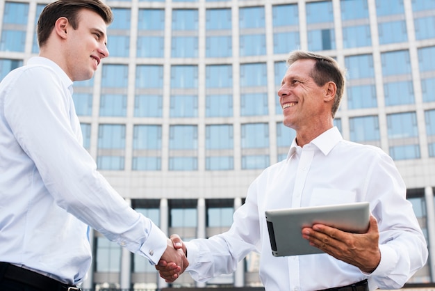 Businessmen shaking hands near building